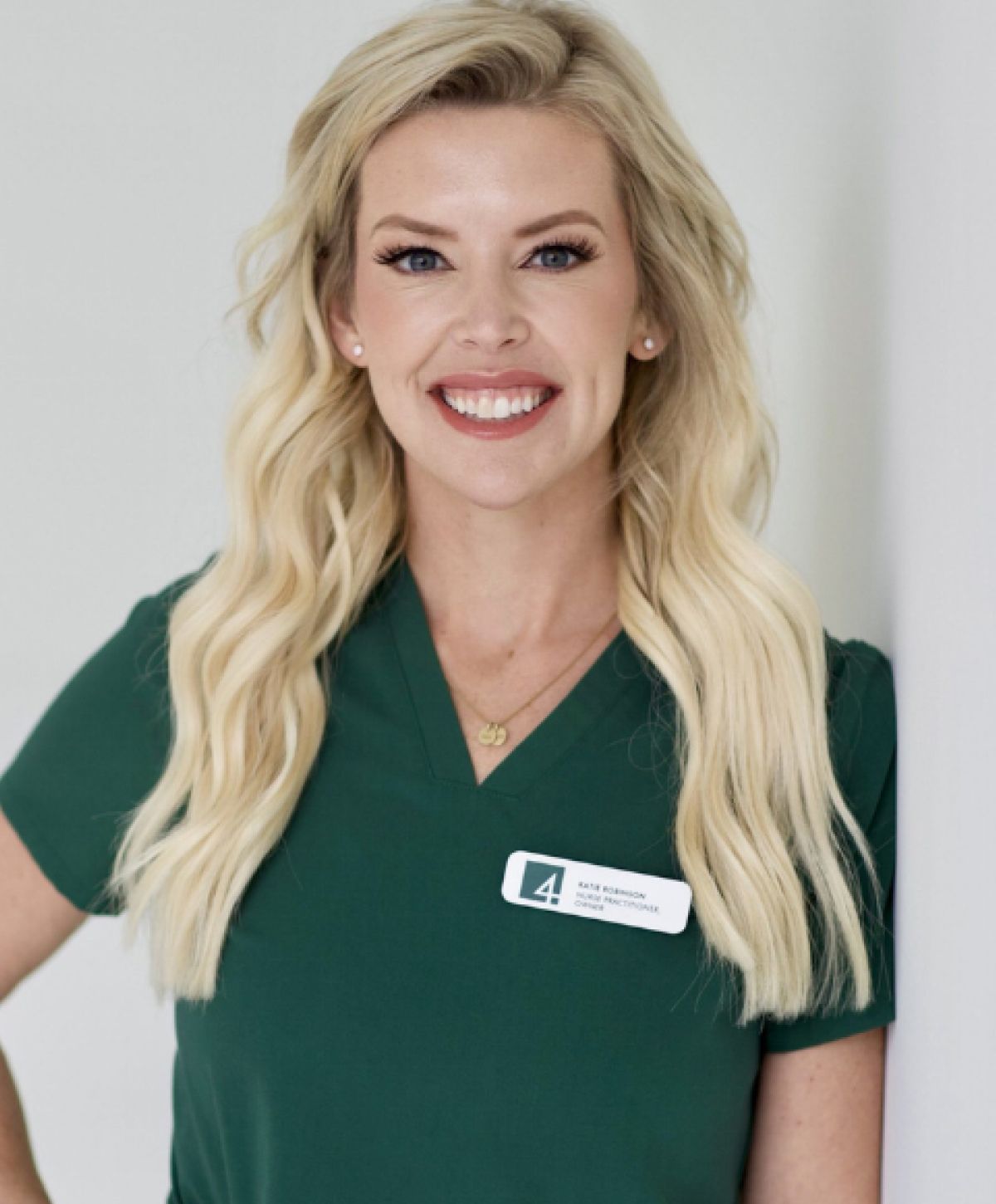 Smiling woman in green uniform with ID badge.