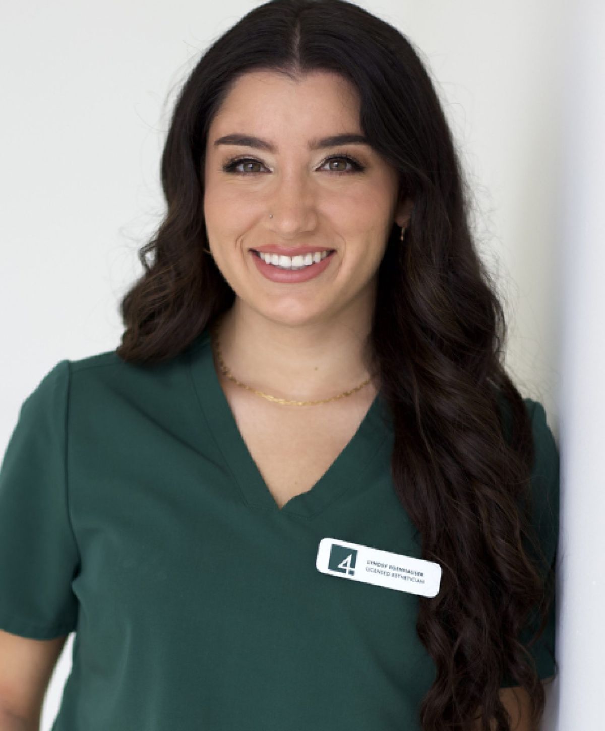 Smiling woman in green scrubs with name tag.