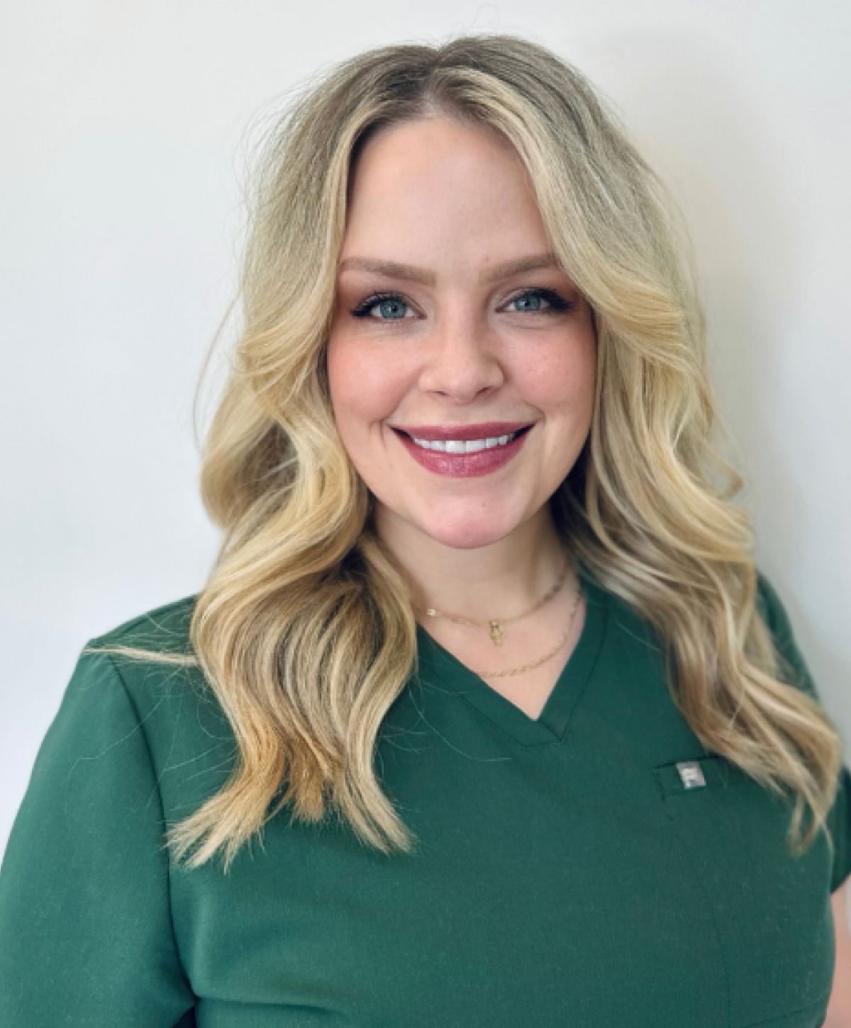 Smiling woman in green medical scrubs.