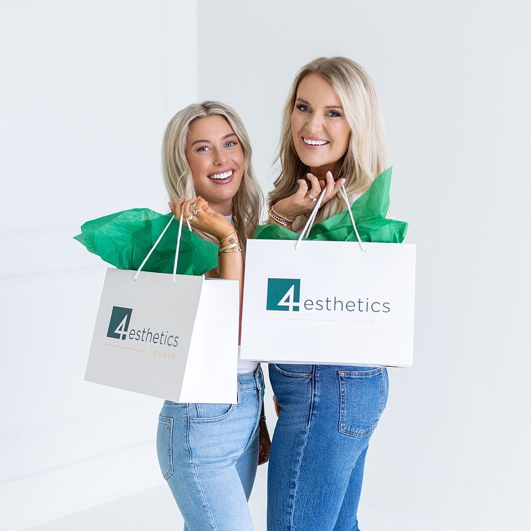 Two women holding shopping bags and smiling.