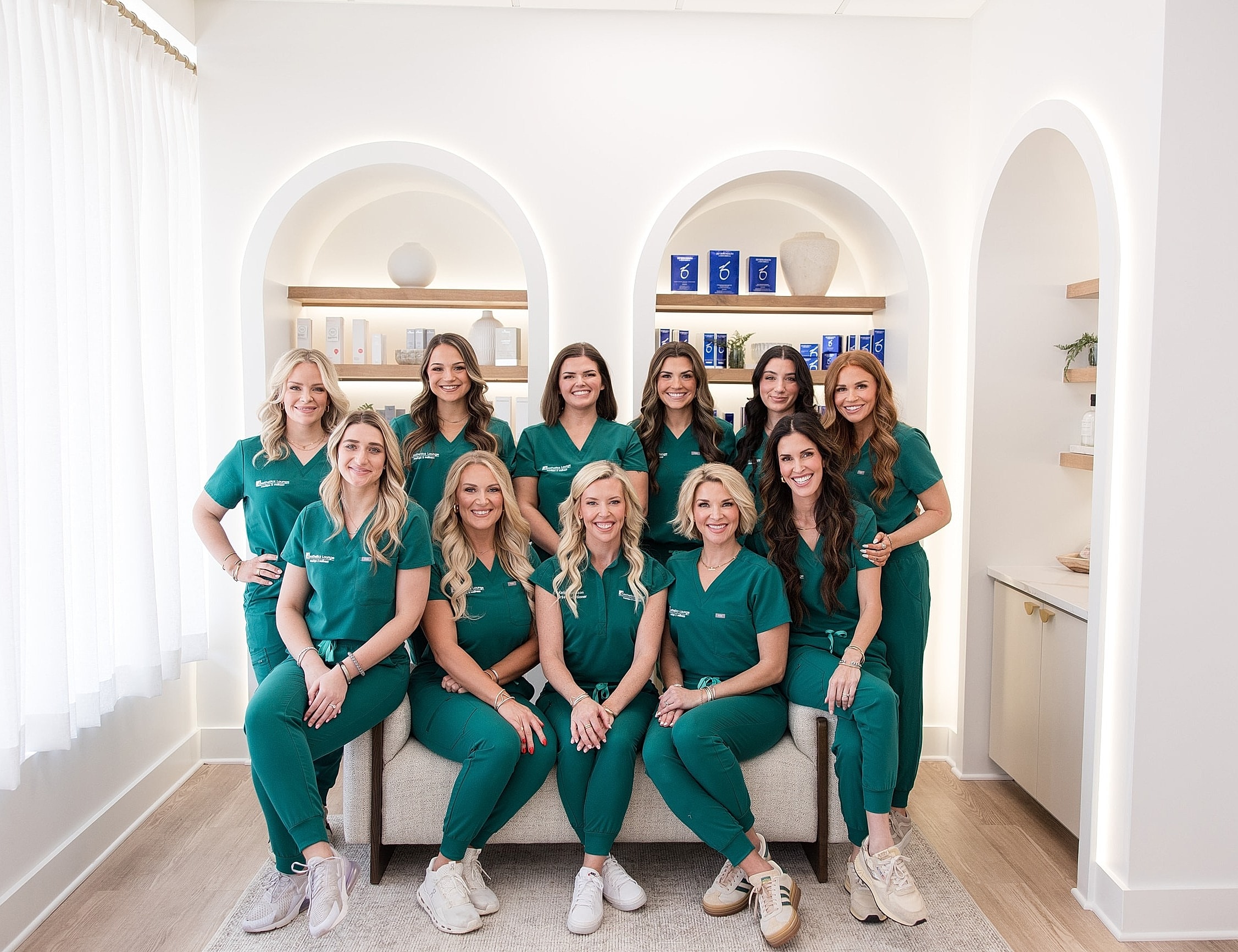 Team of professionals in green scrubs posing together.