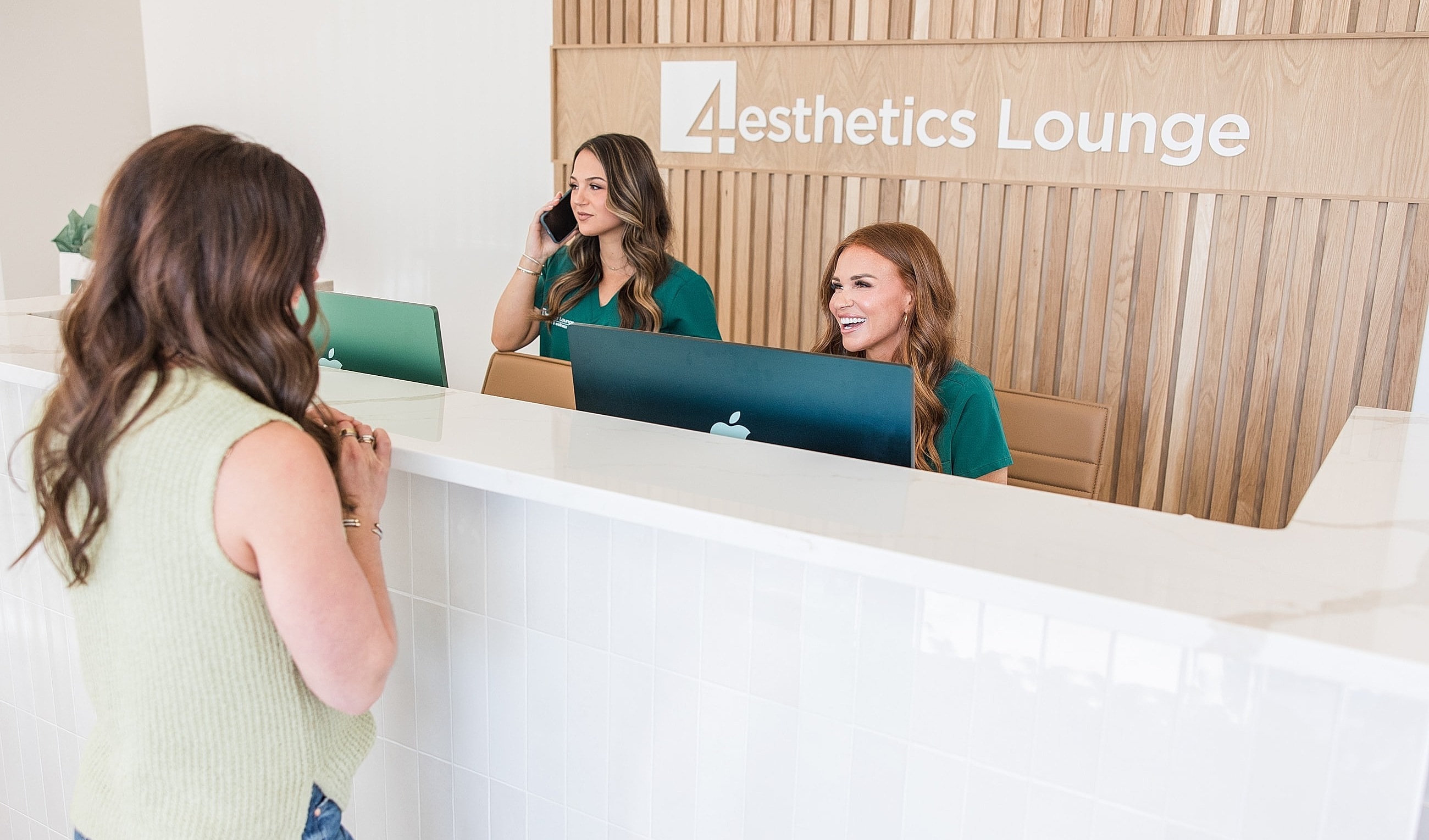 Receptionists assisting clients at aesthetics lounge.