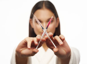 girl holding 2 syringes of filler